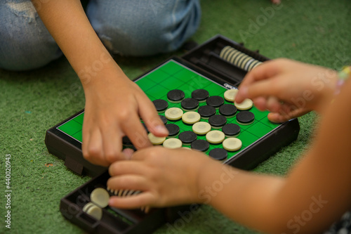 Closeup of kids hands playing reversi or othello traditional strategic board game by thinking, planing and use fingers flip the black reversible disc. Cognitive skills, Mind sport, Competitive concept