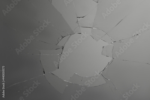 Closeup view of broken glass with cracks on grey background