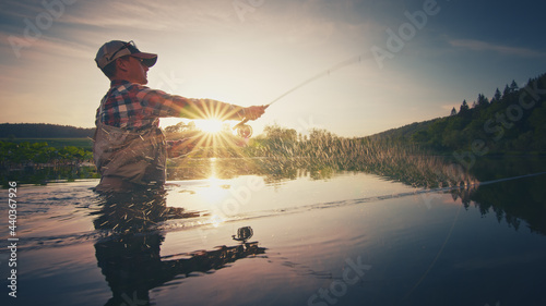 Fly fisherman stands in the water and casts the fly with fishing rod using Roll Cast with lot of splashes