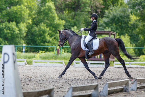 Young sportswoman riding horse on advanced dressage test during the equestrian competition