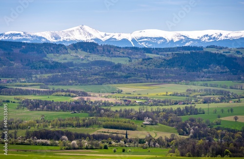 view on Sudety with snowy Karkonosze mountains with green meadows during spring in Poland