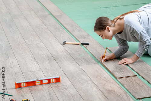 Woman installing laminate flooring in room