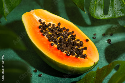 Fresh half of papaya with seeds on tropical leaves background. Tropical exotic fruit.