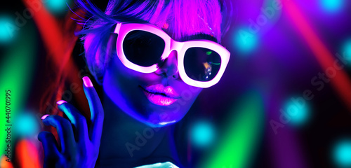 Disco dancer in neon light in night club Fashion model woman in neon light, portrait of beautiful girl with fluorescent make-up, Body Art design in UV, sunglasses, colorful make up. 