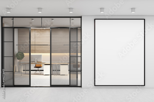 Blank white poster in black frame on light wall near glass doors to sunny stylish eco style interior design office with modern laptops on wooden tables. 3D rendering, mock up