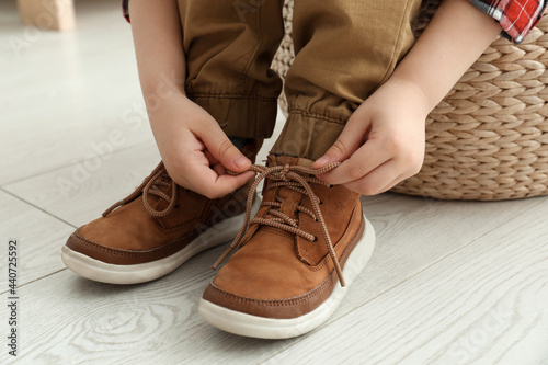 Little boy tying shoe laces at home, closeup