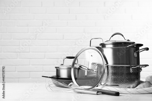 Set of clean kitchenware on white table against brick wall. Space for text