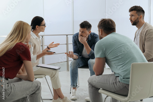 Psychotherapist working with group of drug addicted people at therapy session indoors