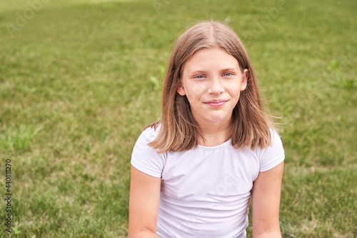 Little girl portrait. Outdoor green background. Looking. Teenager schoolgirl at park. Cute face. Children beauty. Female head. Charisma caucasian