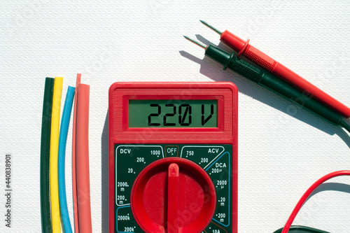 Multimeter with text on display 220 V and heat shrink insulation on white background