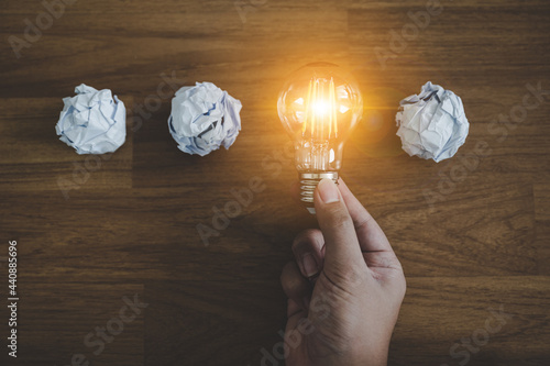 Hand choose light bulb and crumpled office paper. Concept of inspiration creative idea thinking and future technology innovation