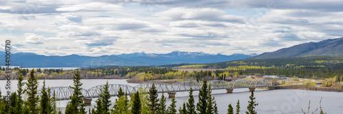 TESLIN, YUKON, CANADA Nisutlin Bay Bridge seen spanning over the river, body of water in northern Canada with mountain view in the background and large, expansive steel structure with boreal forest.