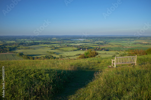 A single empty bench on South Downs National Park overlooking arlington reservoir and the East Sussex Weald.