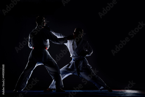 Karate kata training men isolated on dark background