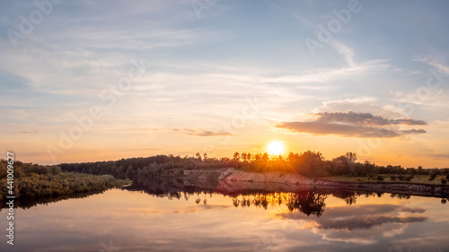 Wide photo of river in the evening in the light of the setting sun. Beautiful landscape of the river