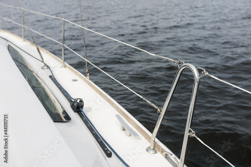 Boat trip on the river. Details about the sailing yacht. In the summer, we go by boat. A white yacht with full sails. Leisure, sports, recreation theme. Close-up view of the metal railing.