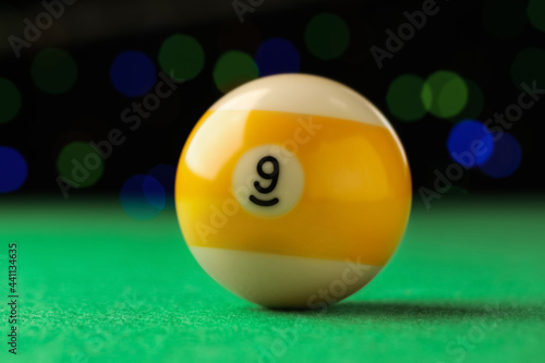 Billiard ball with number 9 on green table, closeup