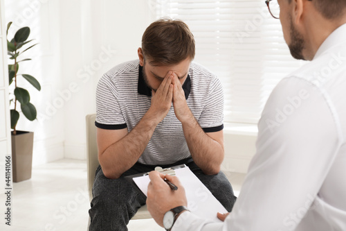 Psychotherapist working with drug addicted young man indoors