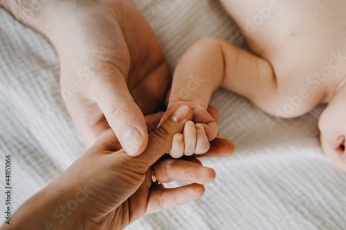 Father and mother holding small newborn baby hand, closeup.