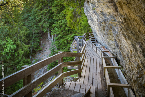 Wooden walking trail on cliff following historic irrigation channel Bisse du Ro in canton of Valais
