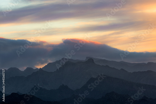The outline of the mountains is drawn with the sun and clouds in the dawn light in Anaga, Santa Cruz de Tenerife, Canary Islands.