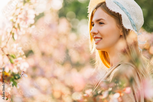 romantic image of tender young woman, in hat, happy smiling woman with spring flowers in the garden, spring concept