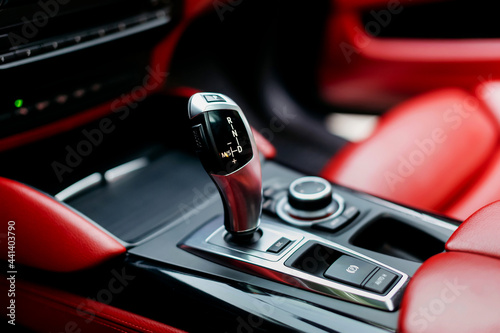 Automatic gear stick of a modern car. Modern car interior details. Close up view. Automatic transmission lever shift. Red leather interior.