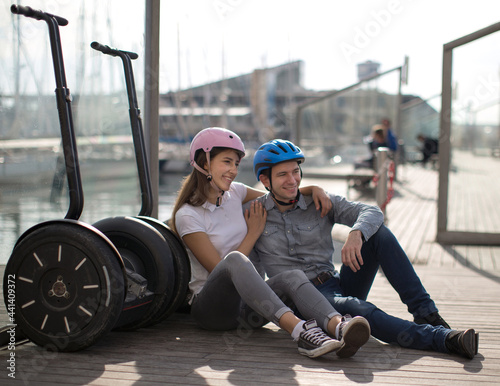 young couple guy and girl are walking on the segway along the board paved promenade in the port of a European city