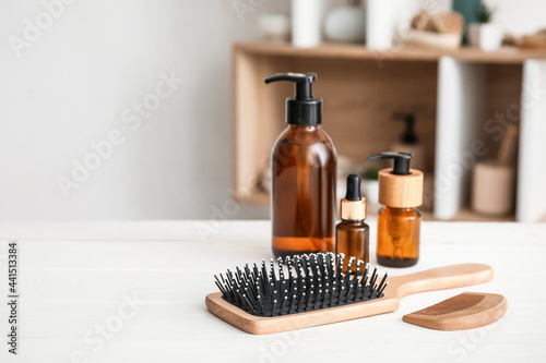 Hair brush, comb and cosmetics on table in room