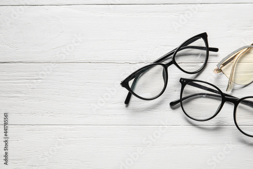 Different stylish eyeglasses on white wooden background