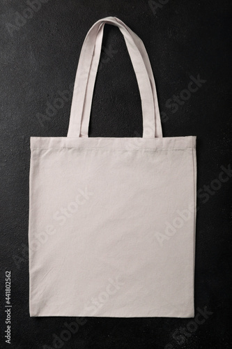 White shopper bag canvas fabric cloth eco shopping sack mockup for your design, template isolated on black textured background with copy space. Flat lay