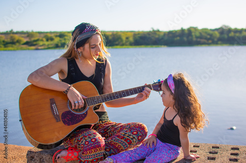 mamá e hija cantando y tocando la guitarra al aire libre 