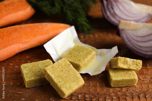 Bouillon cubes and other ingredients for soup on wooden table, closeup