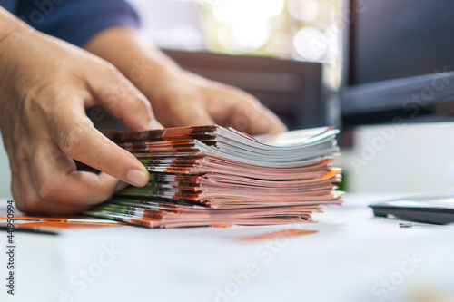 Pile of presentation brochure document concept : Businessman hands working in business Documents on Stacks Brochures papers files for checking achieves reports on busy work computer desk office