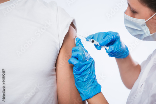 Girl doctor holds a syringe and makes an injection to a patient in a medical mask. Covid-19 or coronavirus vaccine. Masked man receiving coronavirus vaccination graft