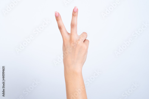 hands with pink manicure over white background pointing up with fingers number two.