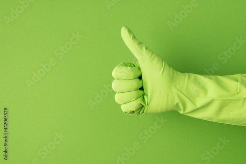 Profile photo of hand in green glove making thumb-up on isolated green background with copyspace