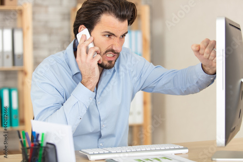 businessman complaining on the phone about problems with laptop