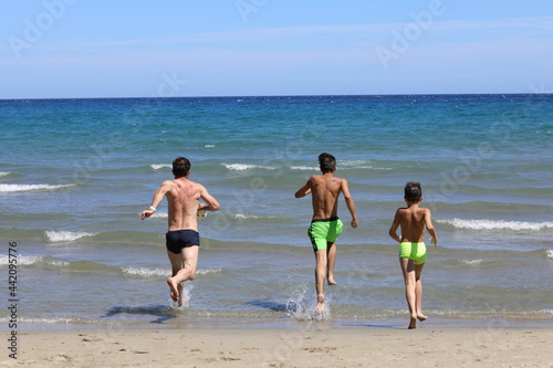 Tata i synowie podczas wygłupów na plaży. Dad and sons on the beach.