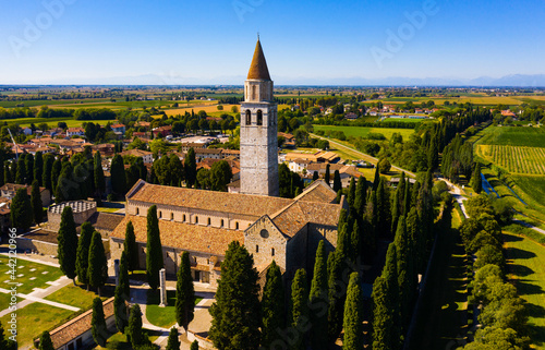 Aerial view of summer landscape of Aquileia township overlooking Basilica di Santa Maria Assunta with Gothic bell tower, Italy