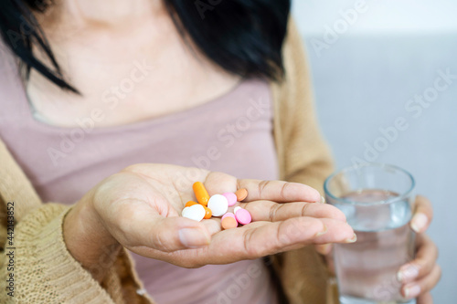 closeup handful of medicines, hand woman hand taking overdose pills with glass of water