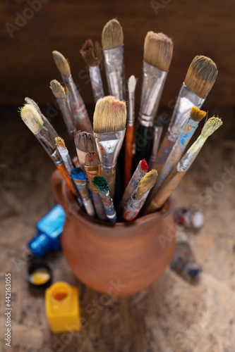 Paint brush in clay jug and painter tool on table background. Paintbrush for painting as art still life