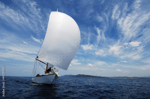 vintage sailboat with white spinnaker sailing downwind