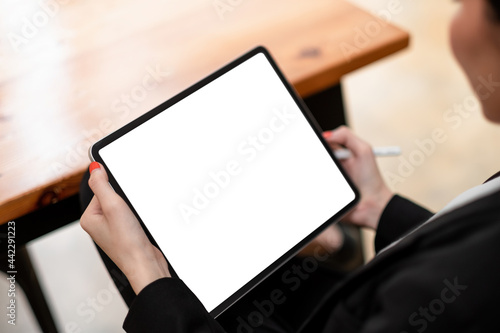 Close-up of woman working with stylus on digital tablet pc with blank white screen