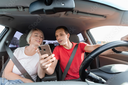 Young couple driving car and using digital map on smartphone