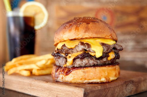 Delicious homemade cheeseburger or hamburger on wooden tray with coke and fires.