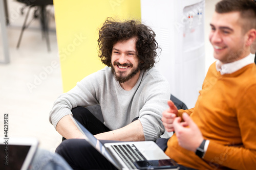 young businessman with clumsy hair smiling on a brainstorming meeting with colleagues at succesful startup company.