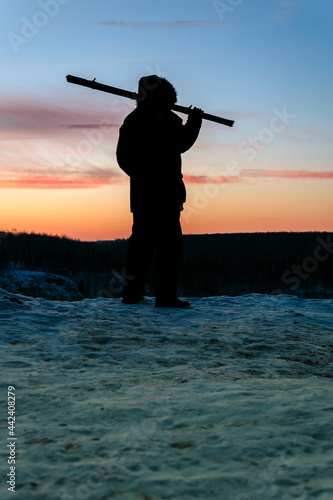 silhouette of a man standing on a rock during sunset in winter