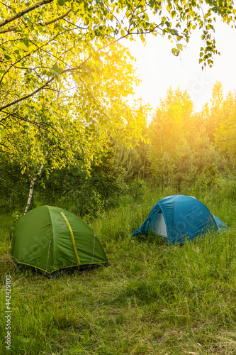 Concept of vacation away from people. Two tents stay near the forest on sunset. Camping. Social distancing.