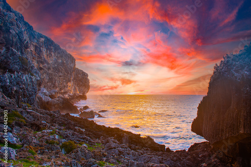 sunrise captured at the bluff in Cayman Brac in the Cayman Islands. The light from the sun has lit the rocky cliff face as well as the clouds above